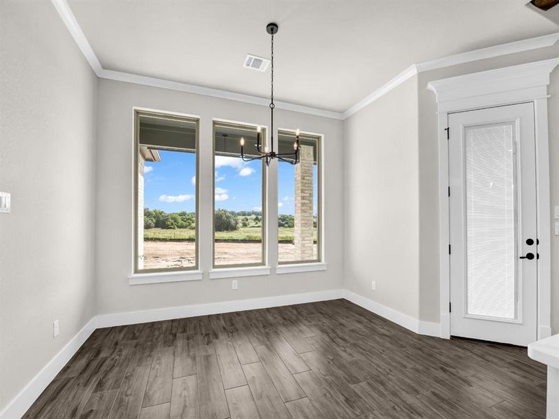 Unfurnished dining area featuring crown molding, a chandelier, and dark wood-style floors