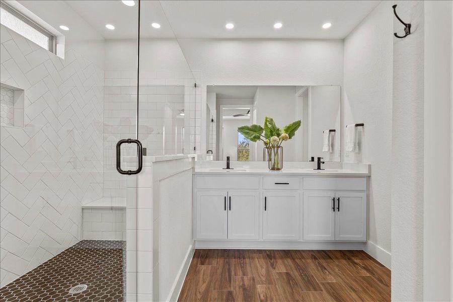 Full bathroom featuring double vanity, dark wood-type flooring, a stall shower, and recessed lighting
