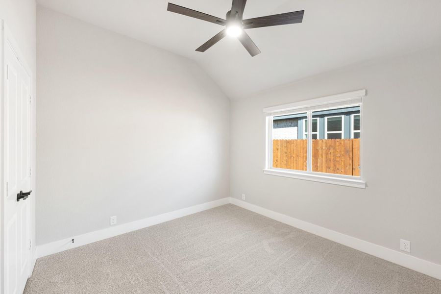 Empty bedroom with vaulted ceiling, ceiling fan, carpet flooring, and single window