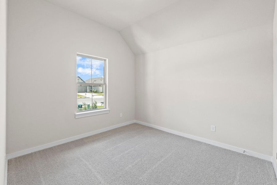 A well-lit bedroom features plush carpeting and a sloped ceiling, ready for personal touches.