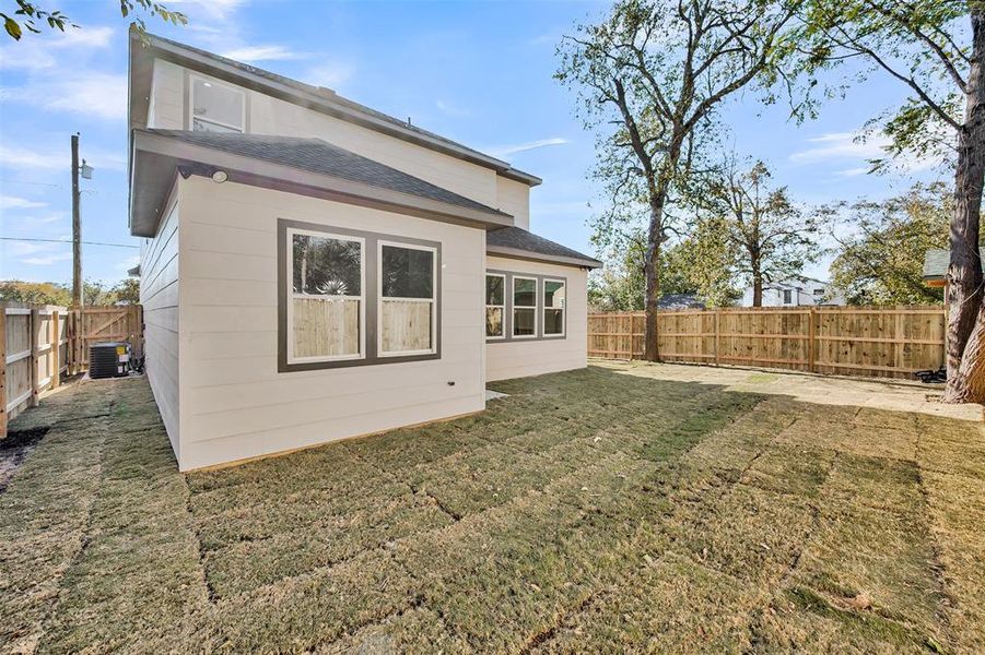 Rear view of house with roof with shingles and a fenced backyard