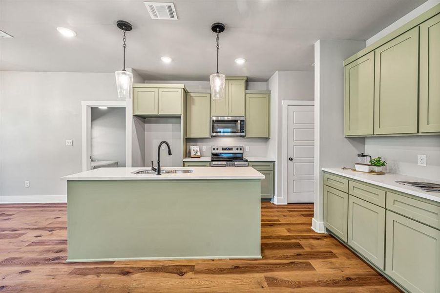 Kitchen featuring green cabinetry, appliances with stainless steel finishes, decorative light fixtures, recessed lighting, and dark wood finished floors Kitchen featuring green cabinetry, appliances with stainless steel finishes, decorative light fixtures, recessed lighting, and dark wood finished floors