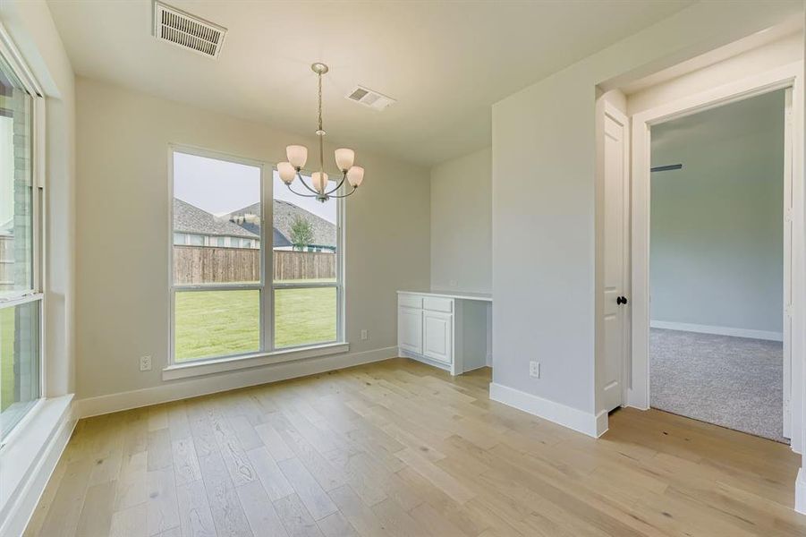Unfurnished dining area with a chandelier and light wood finished floors