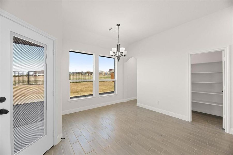 Unfurnished dining area featuring wood tiled floors, a chandelier, arched walkways, and vaulted ceiling Unfurnished dining area featuring wood tiled floors, a chandelier, arched walkways, and vaulted ceiling