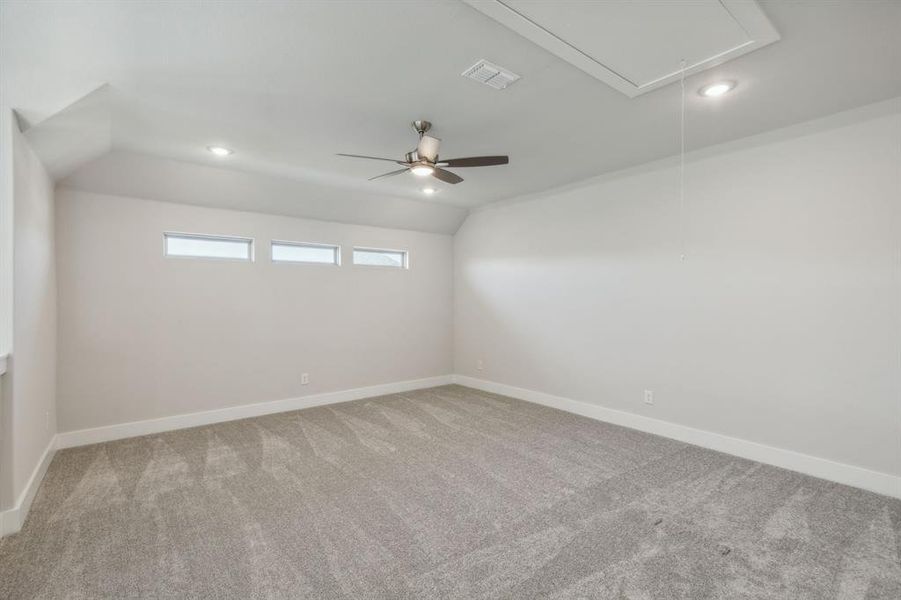 Empty room featuring vaulted ceiling, carpet floors, and ceiling fan