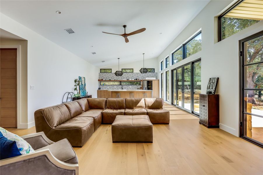 Living room featuring light wood-style flooring, ceiling fan, and high vaulted ceiling