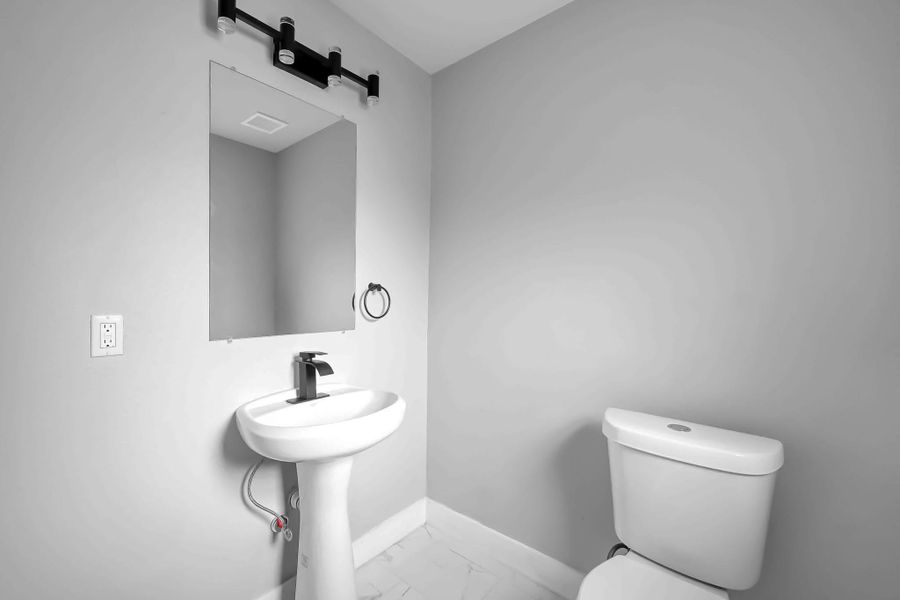 This photo shows a modern, minimalistic bathroom with a pedestal sink, wall-mounted mirror, and toilet. The clean, neutral color scheme and simple lighting create a fresh, inviting atmosphere. This photo shows a modern, minimalistic bathroom with a pedestal sink, wall-mounted mirror, and toilet. The clean, neutral color scheme and simple lighting create a fresh, inviting atmosphere.
