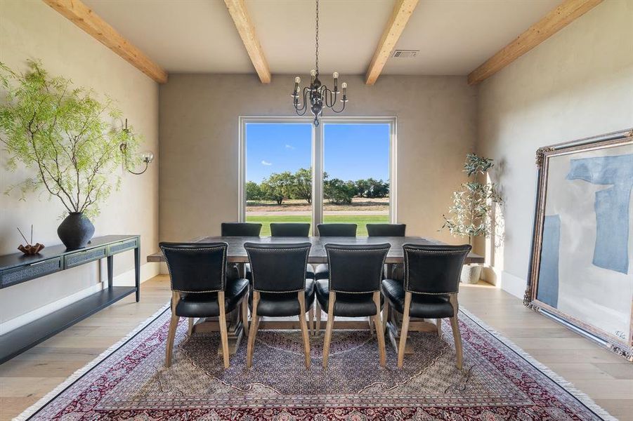 Dining space featuring a notable chandelier, beam ceiling, and light hardwood / wood-style flooring