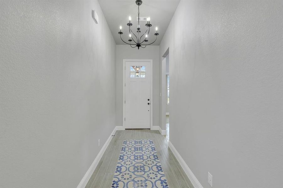 Entryway with a chandelier and a textured wall