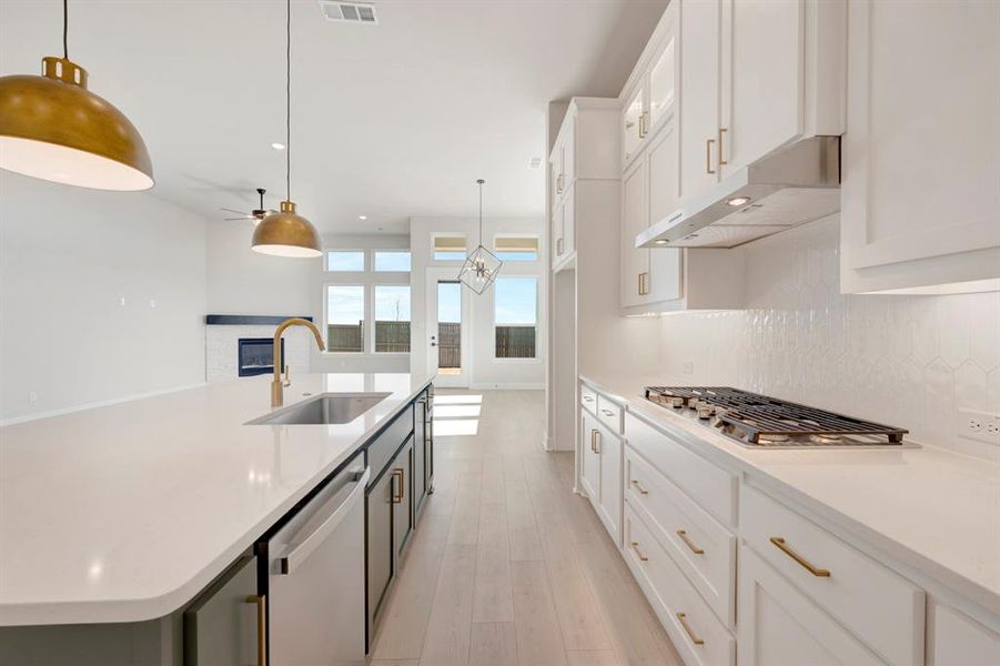 Kitchen with two tone color scheme, a spacious island, stainless steel appliances, a ceiling fan, and hanging light fixtures Kitchen with two tone color scheme, a spacious island, stainless steel appliances, a ceiling fan, and hanging light fixtures