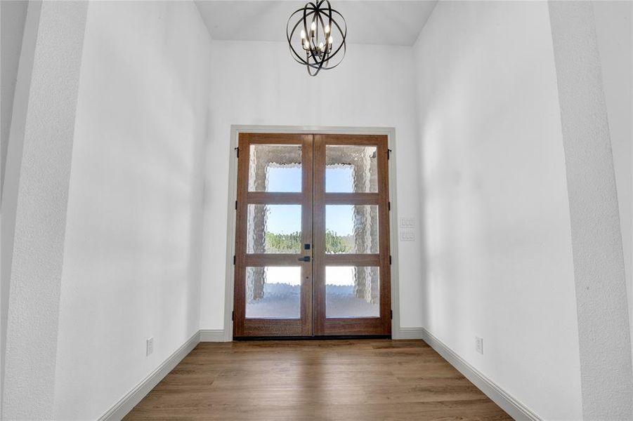 Doorway featuring light hardwood / wood-style floors, a chandelier, french doors, and a wealth of natural light