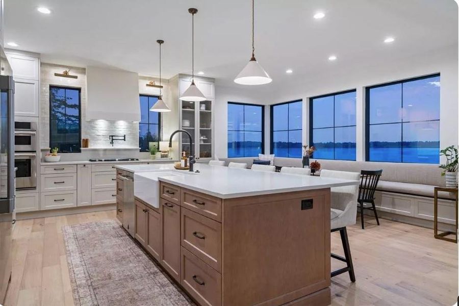 Kitchen with a Oversized island with Farmhouse sink, High-end appliances with stainless steel finishes, Decorative Pendant lighting, Shaker Style Cabinets