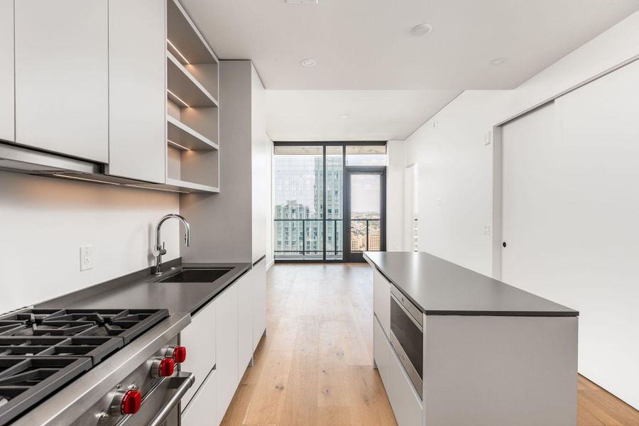 A sleek, contemporary kitchen with premium appliances offers breathtaking cityscape views through expansive glass.