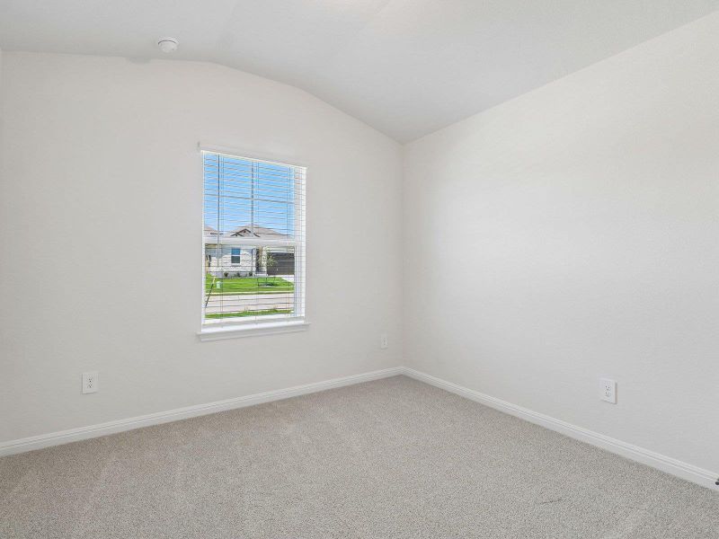 Plush carpeting and a vaulted ceiling elevate this versatile secondary bedroom space.
