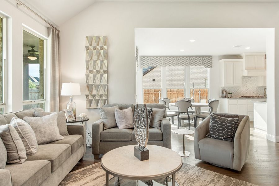 Open-concept living room with gray sofas, hardwood floors, and view into dining area and kitchen