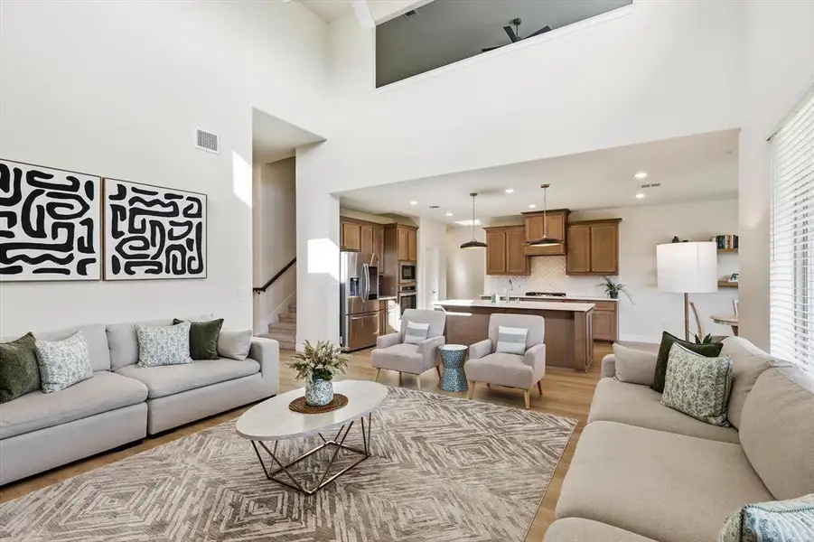 Vaulted ceilings in the open-concept Family room looking into the kitchen with rich wood cabinetry, stainless steel appliances, and a central granite island