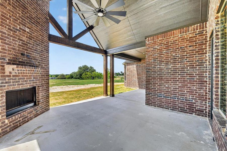 View of patio with a ceiling fan and an outdoor brick fireplace