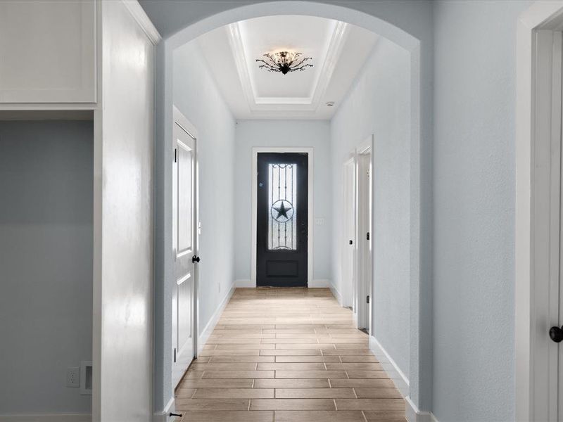 Doorway to outside with a tray ceiling, wood finish floors, and arched walkways