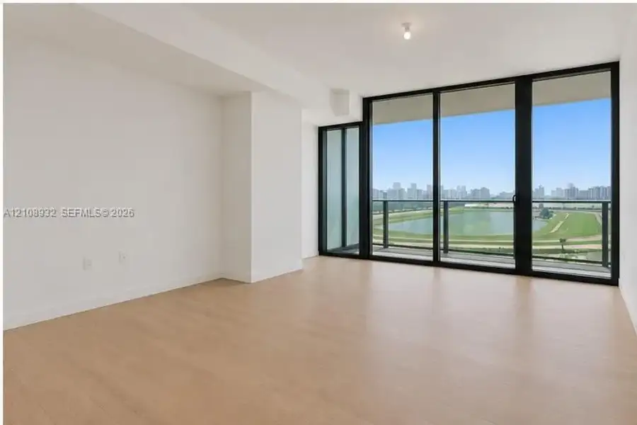 Floor-to-ceiling windows, wood-finish flooring, and access to a balcony with metallic railing