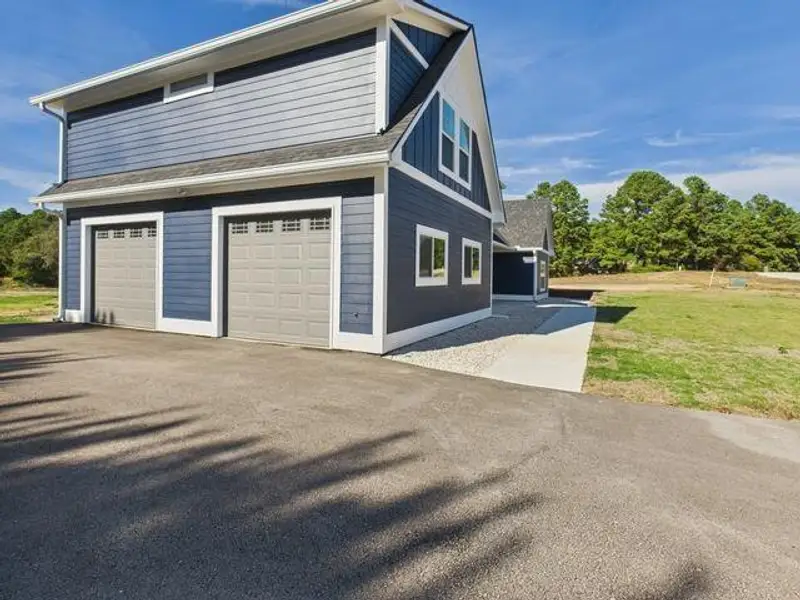 View of home's exterior featuring an attached garage, a yard, and asphalt driveway
