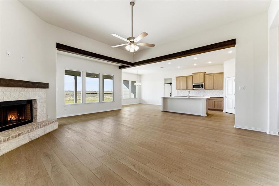 Unfurnished living room featuring a ceiling fan, light wood finished floors, a fireplace, recessed lighting, and a chandelier