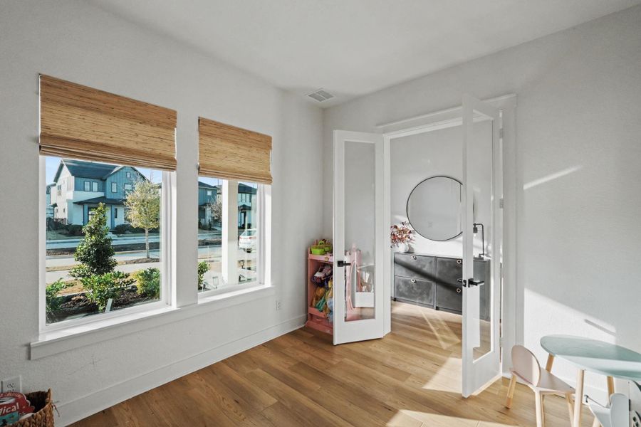 Bright and versatile flex room with beautiful natural light, warm wood flooring, and stylish glass French doors leading to an adjacent bath. Perfect as a home office, nursery, or creative space, this room offers both functionality and charm.