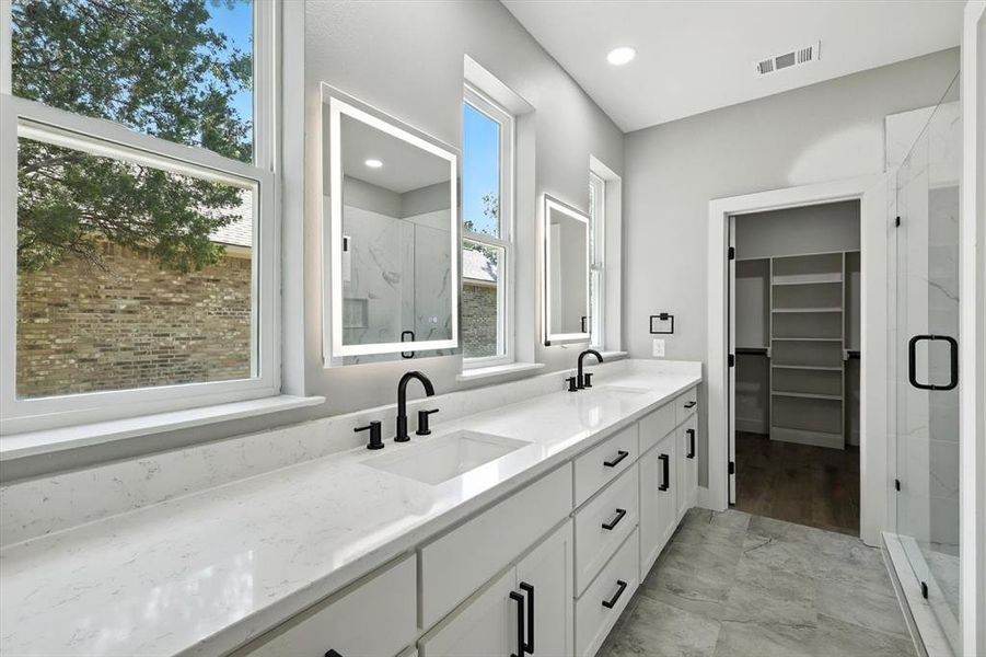 Bathroom with double vanity, a marble finish shower, a walk in closet, and recessed lighting