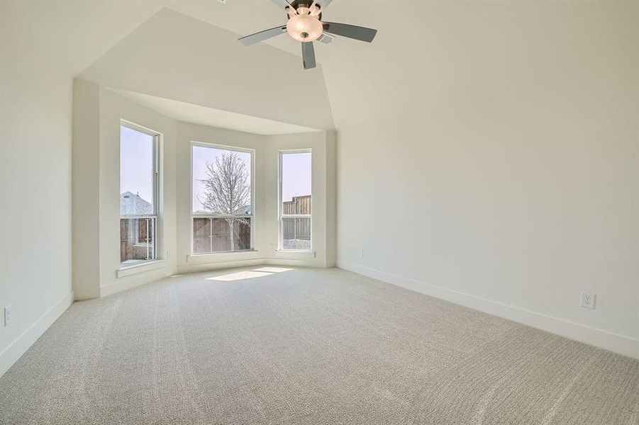 Carpeted empty room with baseboards, ceiling fan, and a towering ceiling