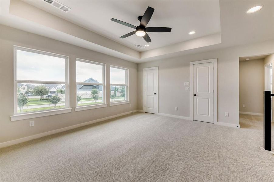 Room featuring three large windows, tray ceiling, recessed lighting, and a contemporary ceiling fan
