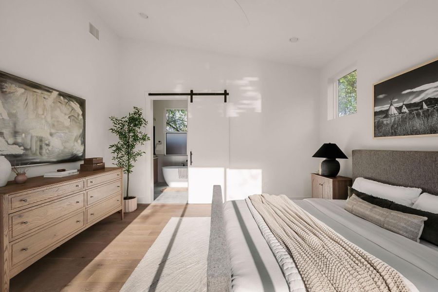 Bedroom featuring a barn door, dark wood-style floors, lofted ceiling, connected bathroom, and ceiling fan Bedroom featuring a barn door, dark wood-style floors, lofted ceiling, connected bathroom, and ceiling fan
