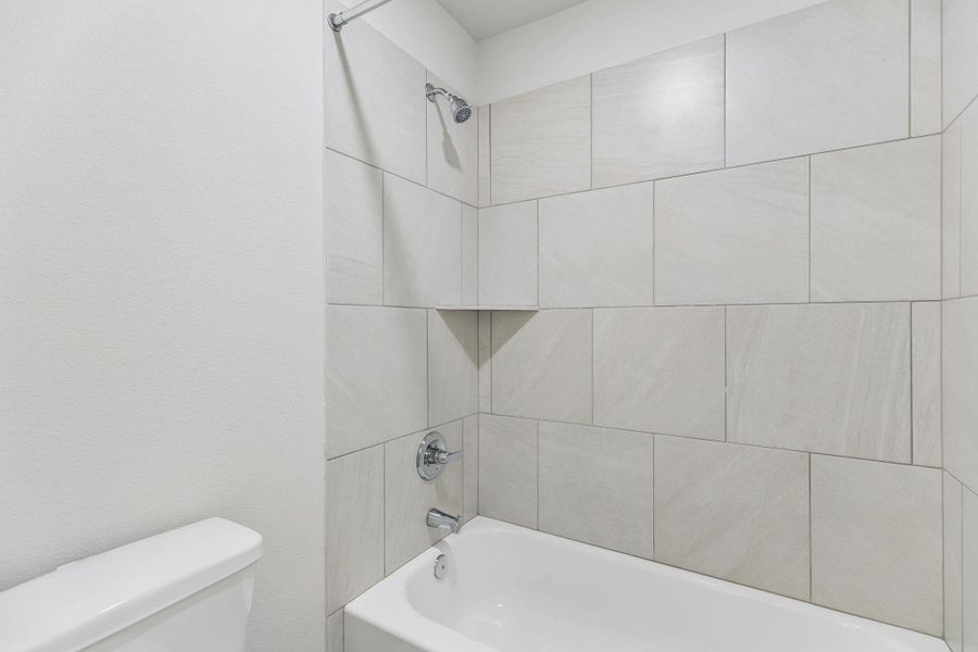 Large tiles line the shower surround in this updated tub and shower combination.