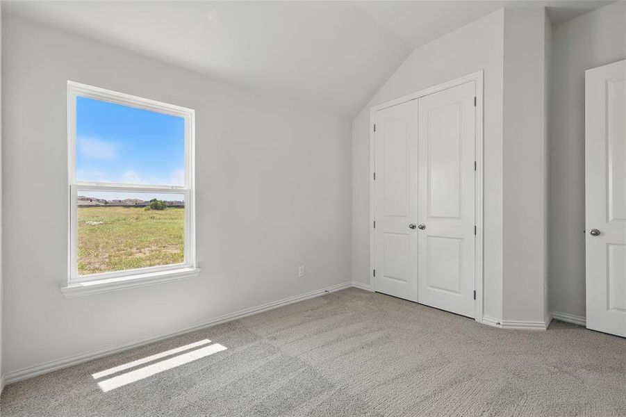 Unfurnished bedroom featuring light carpet, vaulted ceiling, and a closet