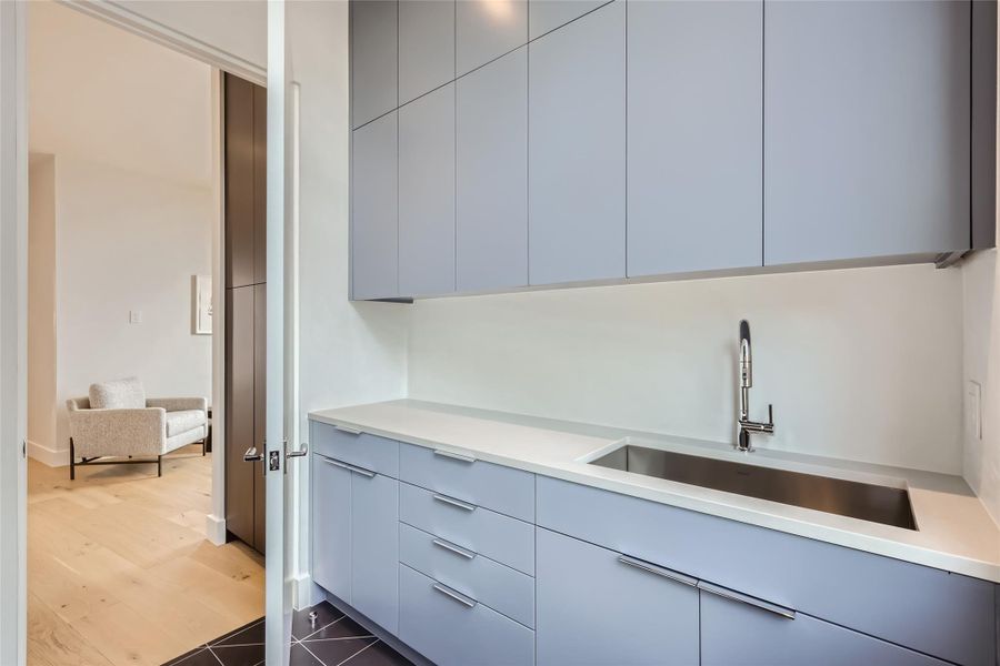 A well-appointed laundry area features clean cabinetry and a utility sink, leading to an adjoining room with warm hardwood floors. A well-appointed laundry area features clean cabinetry and a utility sink, leading to an adjoining room with warm hardwood floors.