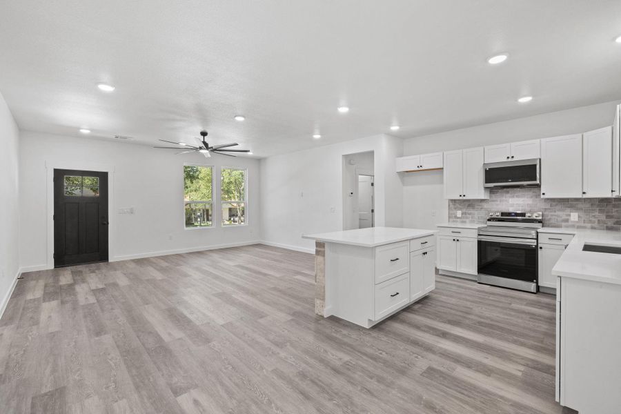 An open concept living area features resilient flooring and abundant recessed lighting. An open concept living area features resilient flooring and abundant recessed lighting.