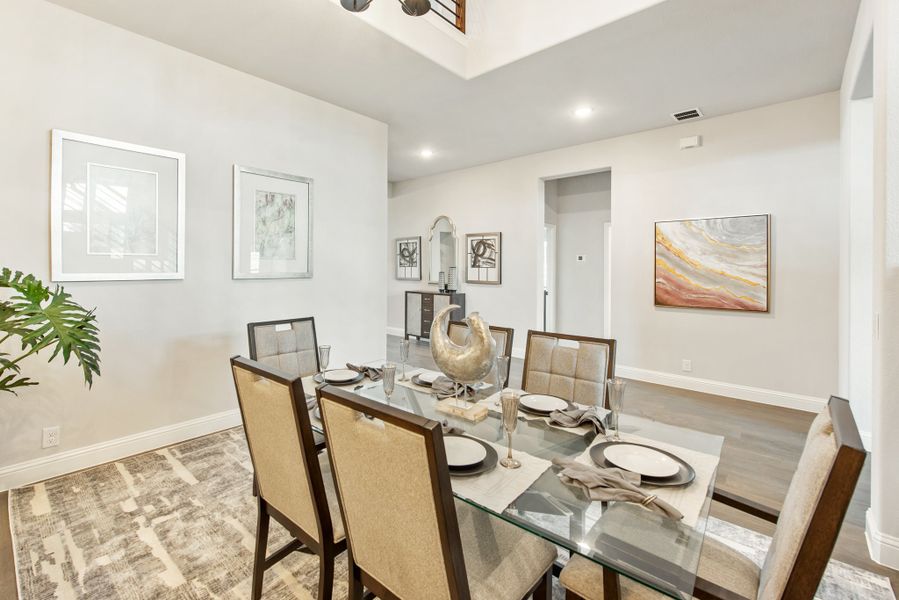 Dining room with glass table, six upholstered chairs, tray ceiling, and framed wall art on light gray walls Dining room with glass table, six upholstered chairs, tray ceiling, and framed wall art on light gray walls