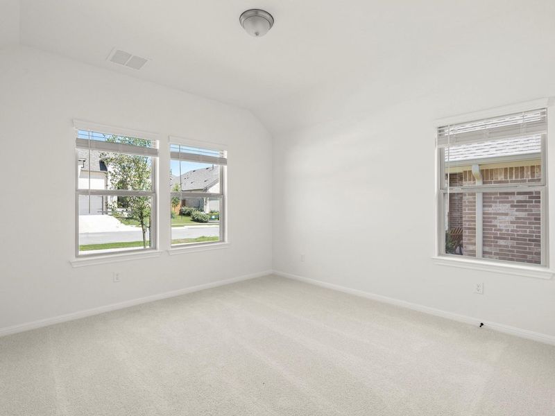 Bright room featuring plush carpet flooring, multiple windows with blinds, a flush-mount ceiling light, and white painted walls