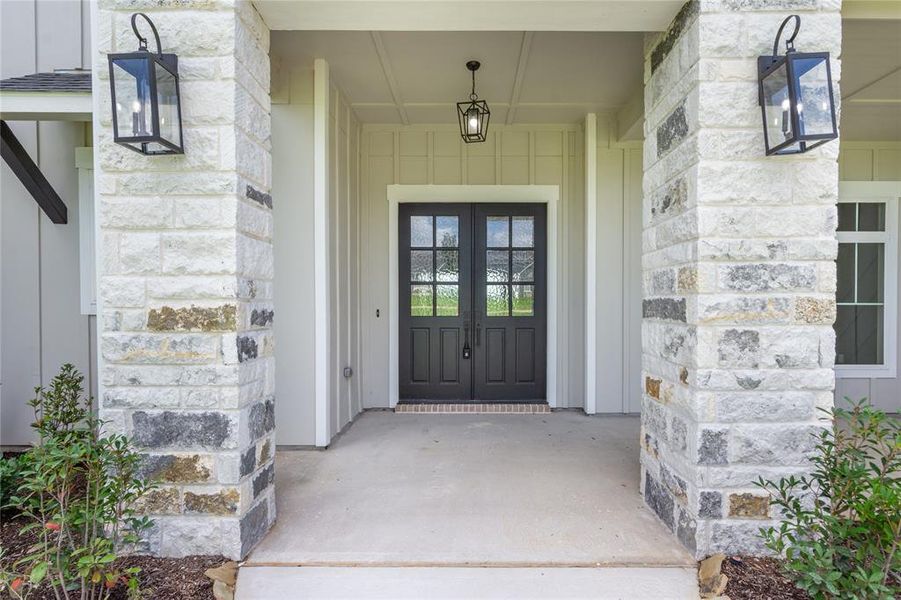 Welcoming front entrance with a double door framed by stone columns, and covered porch Welcoming front entrance with a double door framed by stone columns, and covered porch