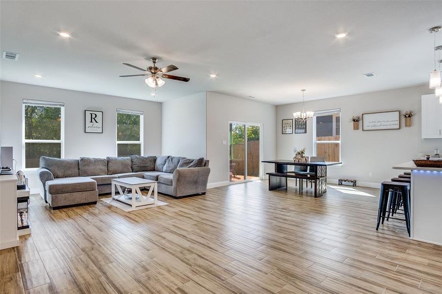 Living room with light wood-style floors, a ceiling fan, recessed lighting, and a chandelier