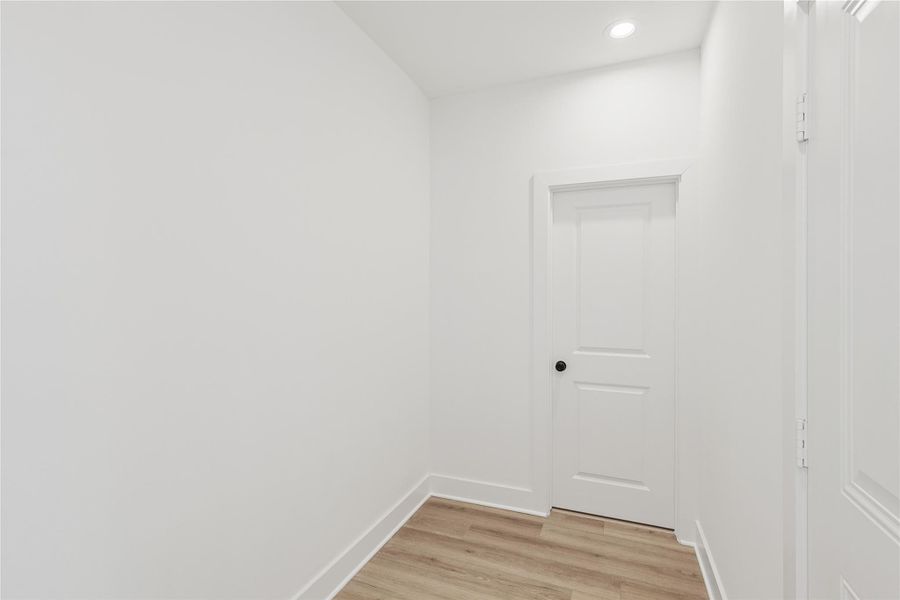 Practical mudroom located just off the garage entry, providing a convenient transition space and easy access to a half bathroom, ideal for everyday use and guest comfort.  The door to the right of the photo is the garage door and straight ahead is the door for the half bathroom.