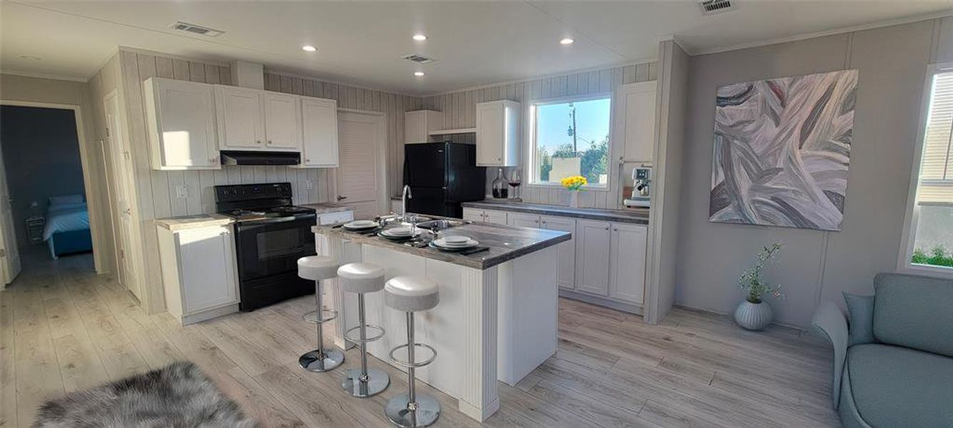 Kitchen featuring visible vents, light wood-style flooring, white cabinetry, and black appliances