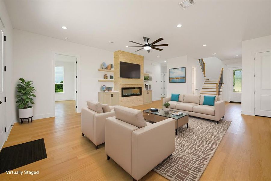 Living area featuring light wood-type flooring, a ceiling fan, a fireplace, and recessed lighting