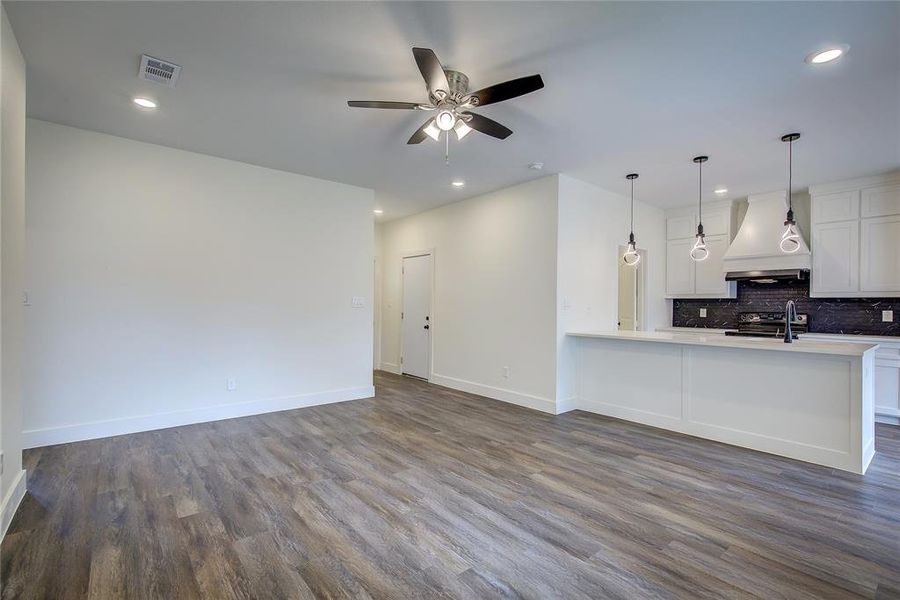 Unfurnished living room with dark wood-style flooring, a ceiling fan, and recessed lighting Unfurnished living room with dark wood-style flooring, a ceiling fan, and recessed lighting