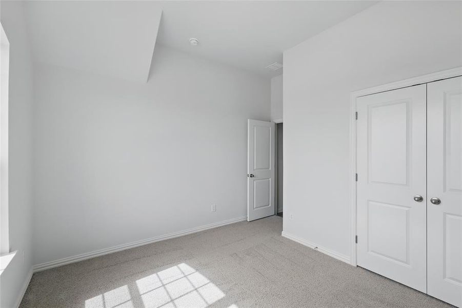 Unfurnished bedroom with light carpet and a closet