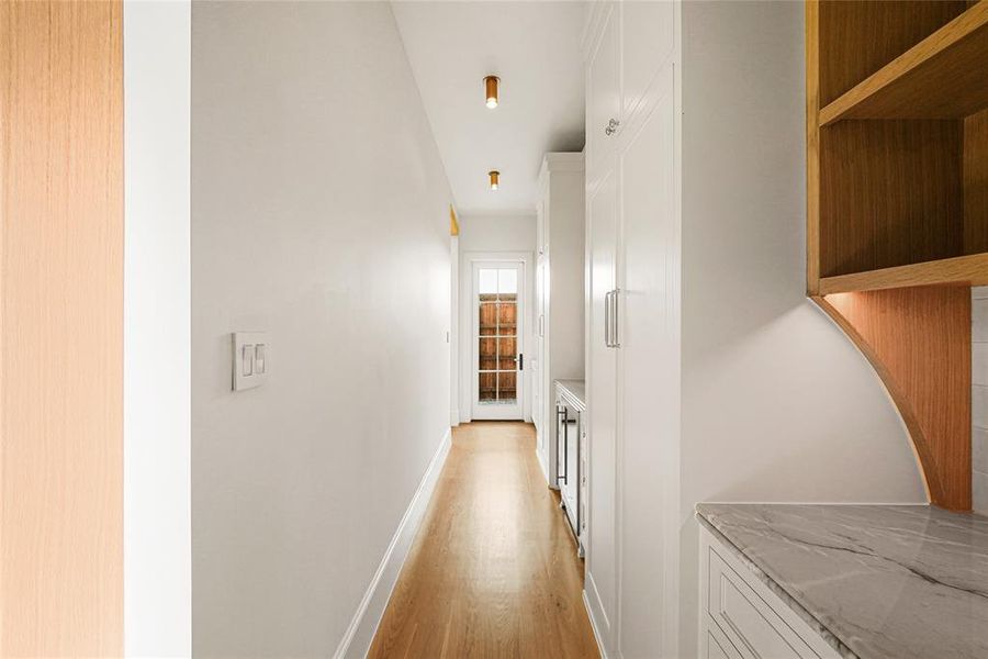 Hallway with wood-finish flooring, recessed ceiling lights, and a full-light paneled door