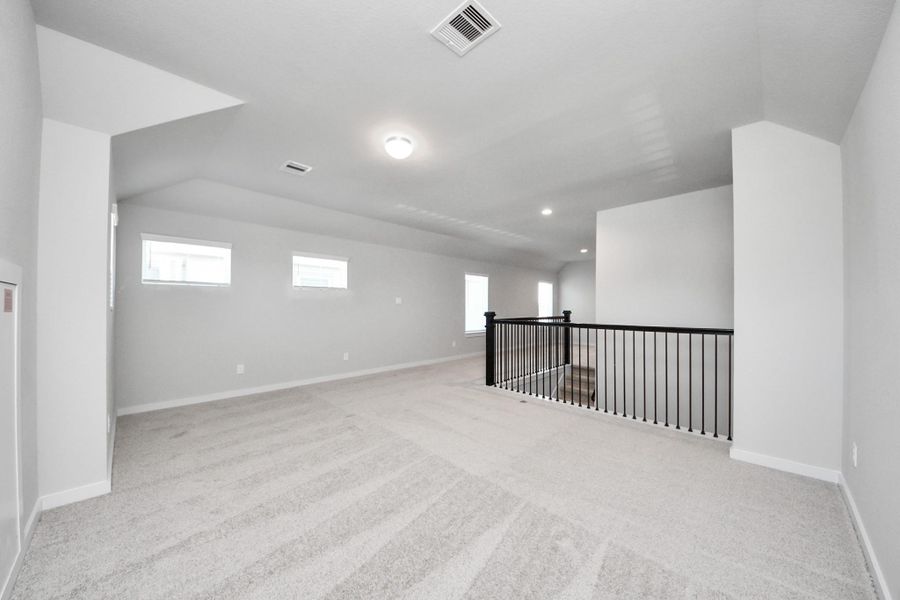 Come upstairs and enjoy a day of leisure in this fabulous game room! This is the perfect hangout spot or adult game room! Features plush carpet, high ceilings, custom paint and windows for plenty of natural light. Sample photo of completed home with similar floor plan. Actual colors and selections may vary.