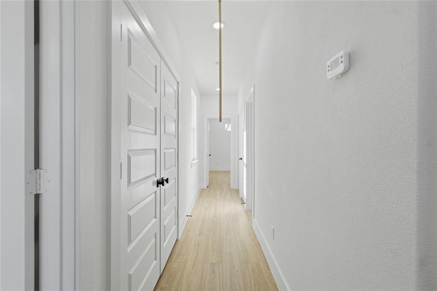 Corridor featuring baseboards and light wood-style flooring Corridor featuring baseboards and light wood-style flooring