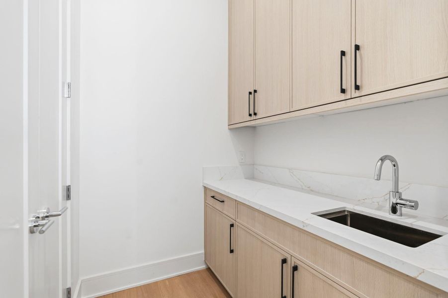 Spacious Butlers pantry with extra sink and abundance of cabinetry.