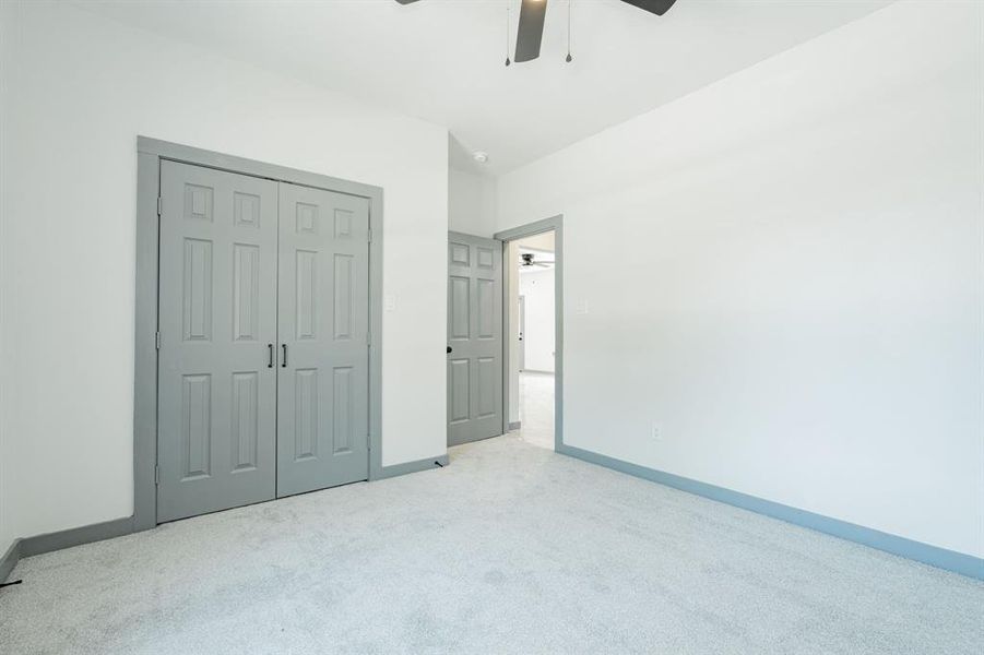 Unfurnished bedroom featuring ceiling fan, a closet, and carpet flooring