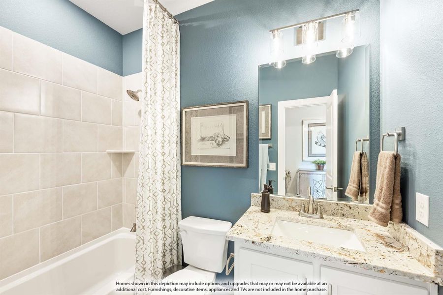 Bathroom with blue walls, granite vanity, white cabinets, and tiled shower-tub combo with curtain
