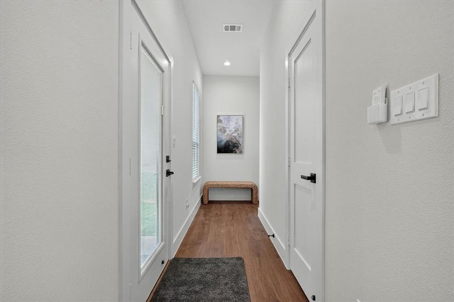 Entry corridor featuring wood-finish flooring, white walls, recessed lighting, and a full-light entry door
